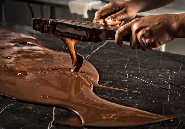 Так шоколатье темперируют шоколад, в результате этого процесса охлаждения на поверхности масло какао затвердевает в определенной кристаллической структуре и не дает ему таять. - Sputnik Беларусь