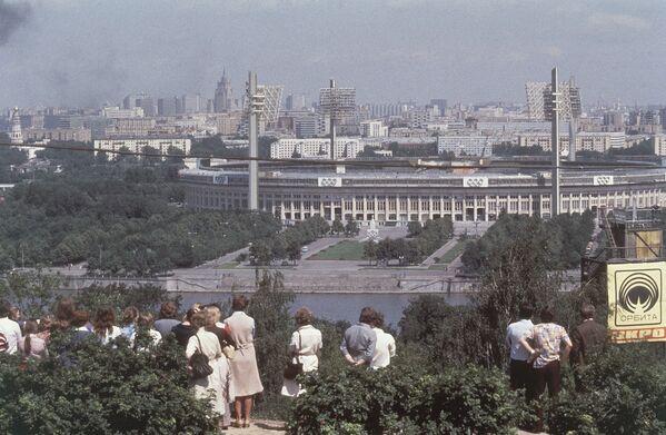 Люди стоят на Ленинских горах, глядя через Москву-реку на центральный стадион имени Ленина с огромными прожекторами, июль 1980 года. - Sputnik Беларусь