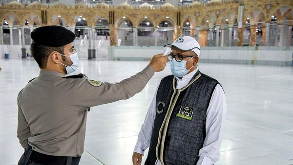 Охранник проверяет температуру у сотрудника перед началом работ в мечети Масджид аль-Харам в Мекке - Sputnik Беларусь
