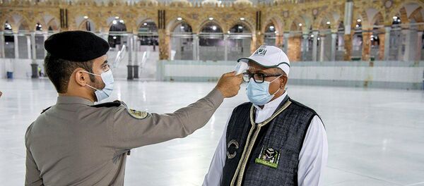 Охранник проверяет температуру у сотрудника перед началом работ в мечети Масджид аль-Харам в Мекке - Sputnik Беларусь