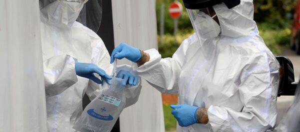 Медицинский персонал обрабатывает образец на месте тестирования на наличие коронавирусной болезни в Бельгии - Sputnik Беларусь