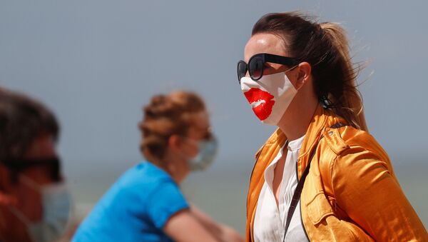 Люди в защитных масках прогуливаются по пляжу в Бельгии, архивное фото - Sputnik Беларусь
