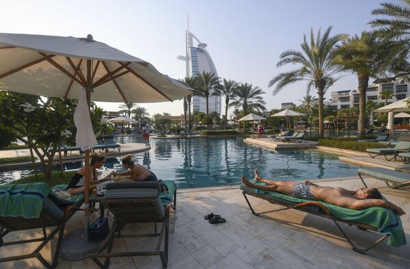 Туристы загорают у бассейна отеля Al Naseem в Дубае в Объединенных Арабских Эмиратах - Sputnik Беларусь