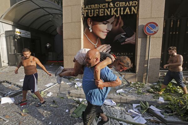 Мужчина уносит раненую девочку из завалов в районе Ахрафия в центре столицы Ливана Бейрута - Sputnik Беларусь