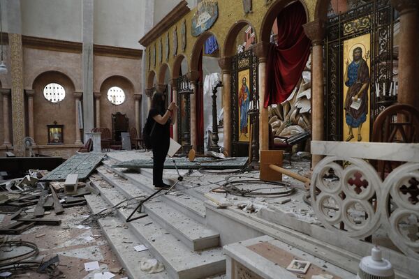 Женщина фотографирует поврежденную церковь на следующий день после взрыва в морском порту Бейрута - Sputnik Беларусь
