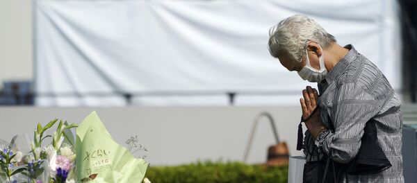 Посетитель молится перед кенотафом о жертвах атомной бомбардировки возле Хиросимского мемориального музея мира - Sputnik Беларусь