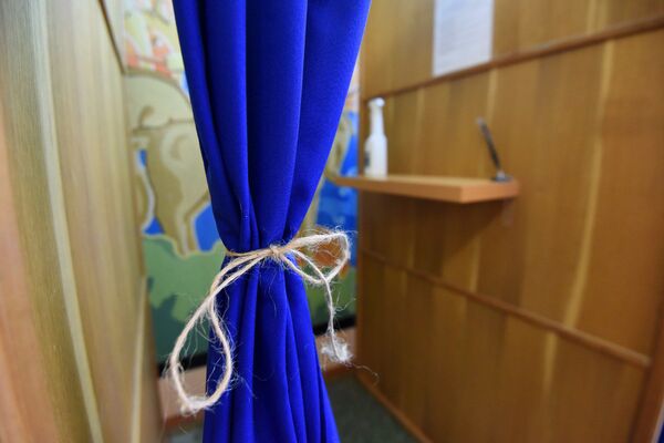 На многих участках для голосования шторки в кабинках остались, но их подвязали тесьмой, чтобы избиратели не касались ткани руками - Sputnik Беларусь