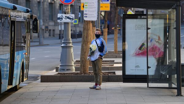 Мужчина в маске с букетом цветов на остановке общественного транспорта - Sputnik Беларусь