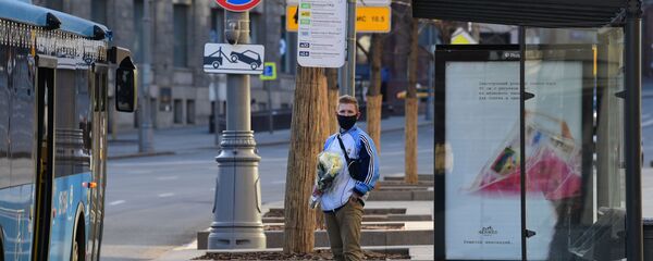 Мужчина в маске с букетом цветов на остановке общественного транспорта - Sputnik Беларусь