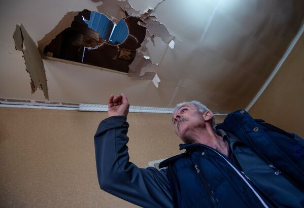 Мужчина показывает дом, поврежденный в результате обстрела по общине Иванян Нагорного Карабаха - Sputnik Беларусь