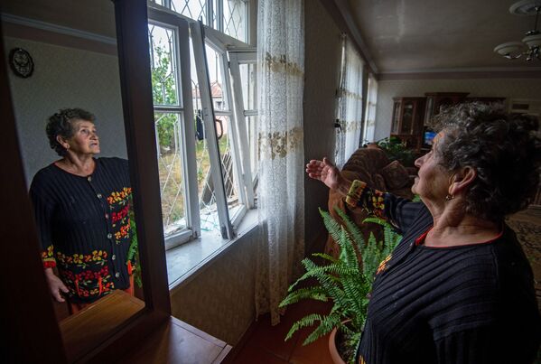 Женщина показывает выбитые окна в результате обстрелов общины Иванян Нагорного Карабах - Sputnik Беларусь