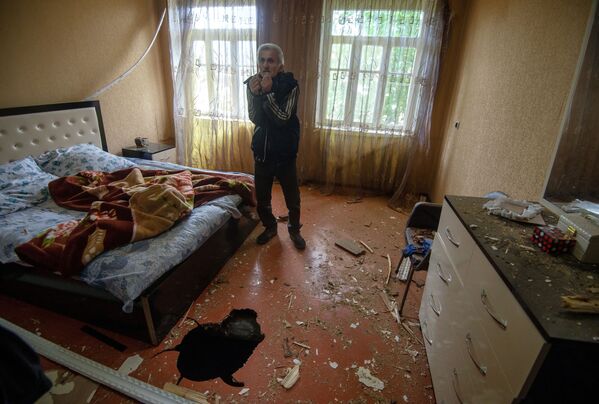Мужчина показывает дом, поврежденный в результате обстрела по общине Иванян Нагорного Карабаха - Sputnik Беларусь