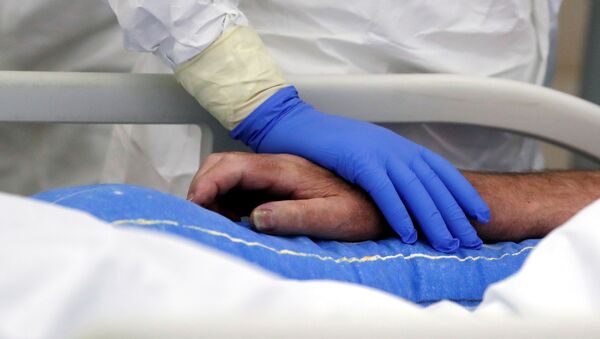Медик держит за руку пациента, больного коронавирусом - Sputnik Беларусь