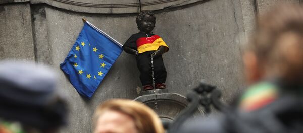 Скульптура Писающий мальчик, одетый в цвета немецкого флага, рядом с флагом ЕС в центре Брюсселя - Sputnik Беларусь