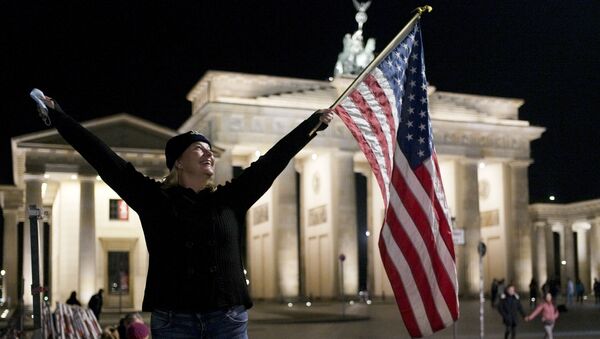 Женщина празднует победу Джо Байдена перед Бранденбагскими воротами рядом с посольством США в Берлине - Sputnik Беларусь
