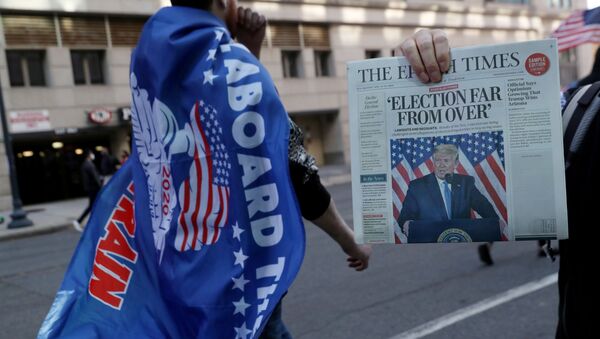 Продавец держит газету во время митинга в поддержку президента США Трампа в Вашингтоне, США, 14 ноября 2020 года - Sputnik Беларусь