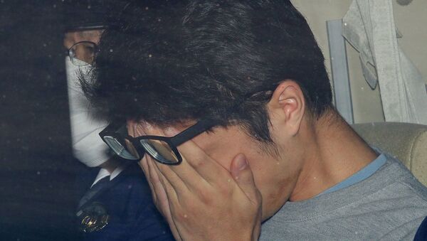 Такахиро Сираиси закрывает лицо в полицейской машине в Токио - Sputnik Беларусь