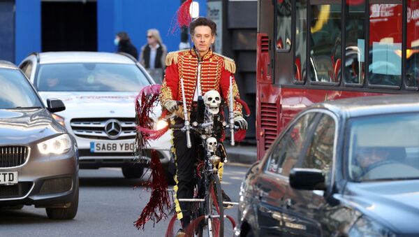 Человек едет на велосипеде с черепами и флагами по Лондону - Sputnik Беларусь