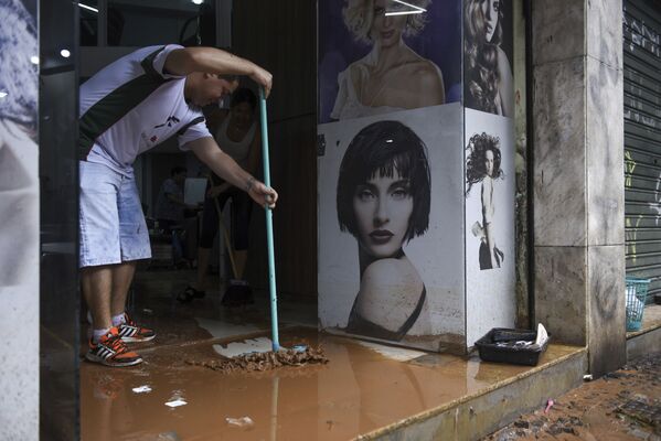 Мужчина убирает грязь с территории магазина, оставшуюся после наводнения в бразильском Белу-Оризонти - Sputnik Беларусь