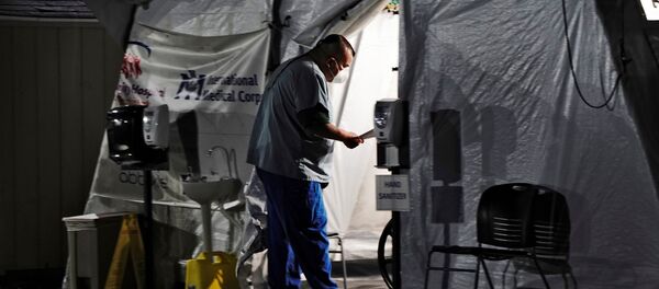 Медицинский работник осматривает пациентов в палатке возле отделения неотложной помощи - Sputnik Беларусь