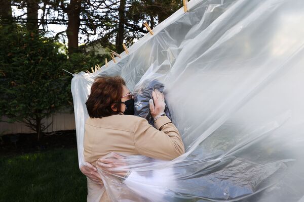 Мишель Грант обнимает свою мать Мэри Грейс Силео через пластиковую шторку - Sputnik Беларусь