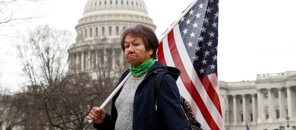 Сторонник президента США Дональда Трампа держит американский флаг во время митинга у Капитолия Сторонник президента США Дональда Трампа держит американский флаг во время митинга у Капитолия - Sputnik Беларусь