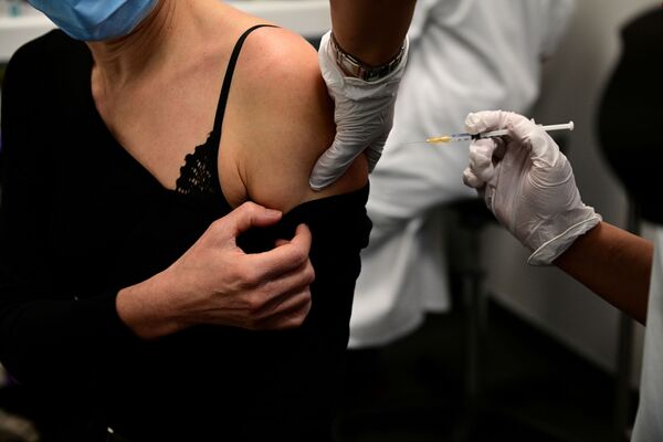 Женщина получает вакцину от COVID-19 во время кампании вакцинации медицинских работников в центре вакцинации в Париже - Sputnik Беларусь