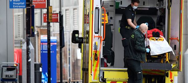 Медицинские работники вывозят пациента из машины скорой помощи в Лондоне - Sputnik Беларусь