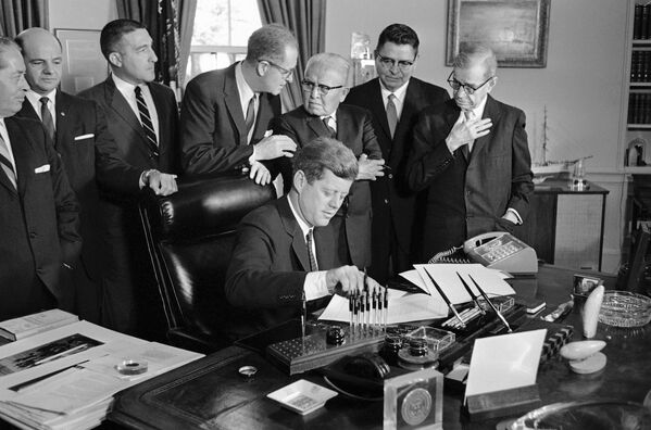 Президент Джон Ф. Кеннеди выбирает ручку, чтобы подписать законопроект, за своим столом в Белом доме, 1962 год. Овальный кабинет при нем оставался таким же, как при двух его предшественниках: Трумэне и Эйзенхауэре. К обновлению кабинета для Кеннеди приступили во время его поездки в Даллас в 1963 году, где президент погиб при покушении. - Sputnik Беларусь