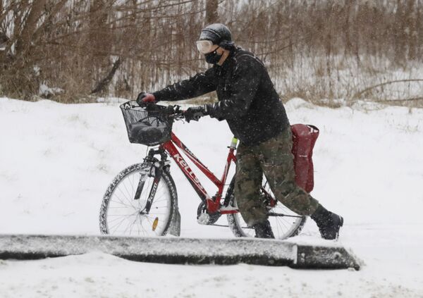 Доставщик еды толкает свой велосипед по свежему снегу недалеко от Варшавы - Sputnik Беларусь