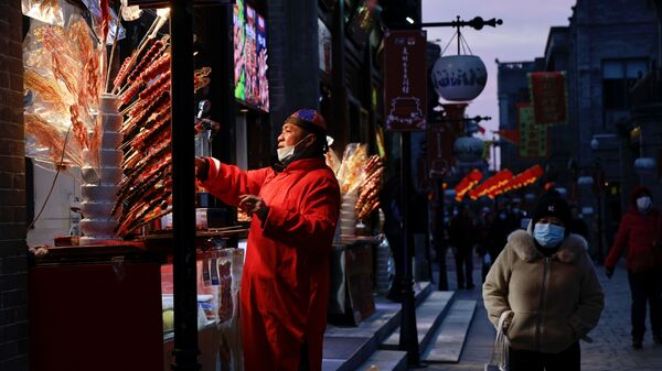 Торговец продает уличную еду Тангулу, традиционную северно-китайскую закуску из засахаренных фруктов, в Пекине - Sputnik Беларусь