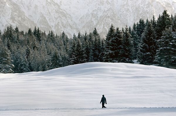 Мужчина идет сквозь снег недалеко от Гармиш-Партенкирхена, Германия - Sputnik Беларусь