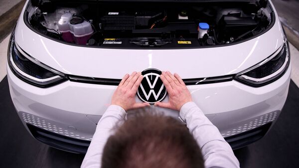 Рабочий устанавливает логотип VW на электромобиле Volkswagen ID.3 на сборочном конвейере автозавода Volkswagen - Sputnik Беларусь