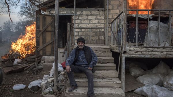 Местный житель Арег сидит у горящего дома в поселке Карегах, Нагорный Карабах. Некоторые жители сожгли свои дома перед тем как уйти - Sputnik Беларусь
