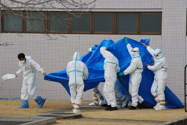 Военнослужащие Японии в костюмах радиационной защиты держат синюю пленку над пациентами, подвергшимися воздействию высокиого уровня радиации - Sputnik Беларусь