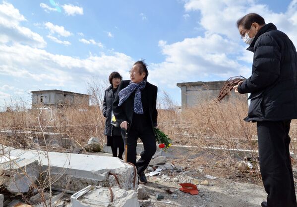Бывшие жители префектуры Фукусима принесли букет цветов на место их дома, снесенного цунами - Sputnik Беларусь