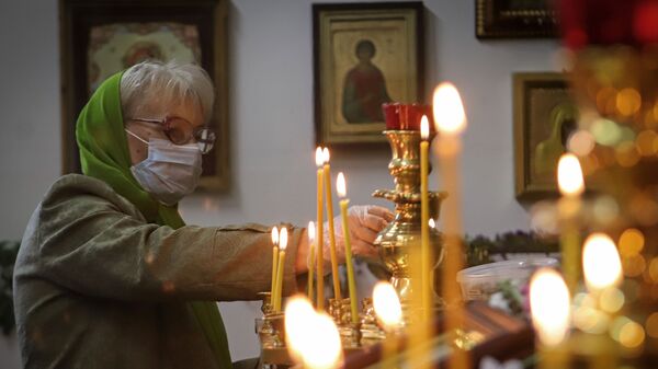 Верующая ставит свечку в храме  - Sputnik Беларусь