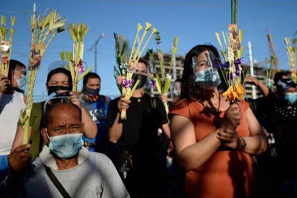 Верующие в защитных масках во время мессы в Вербное воскресенье возле Национального святилища в Паранаке, Филиппины - Sputnik Беларусь