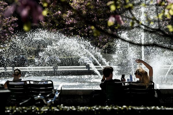 Люди сидят на скамейке перед фонтаном в саду Пале-Рояль в Париже - Sputnik Беларусь