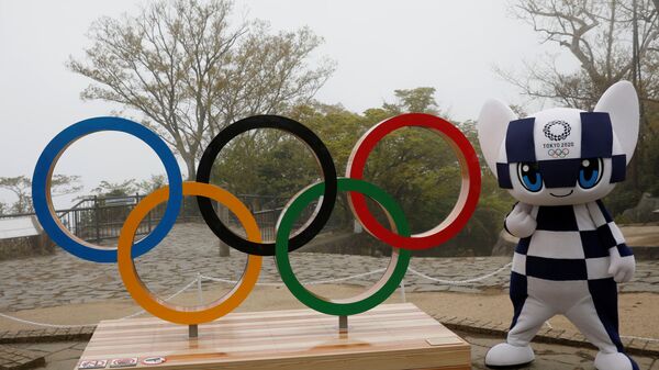 Талисман Олимпийских игр 2020 года в Токио Мираитова позирует с изображением олимпийского символа после церемонии открытия на горе Такао - Sputnik Беларусь