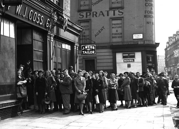 Покупатели выстраиваются в очередь за хлебом на Пимлико-роуд в Челси в Лондоне в День Победы 8 мая 1945 года. Этим утром лондонские лавочники открыли свои двери всего на два часа, чтобы лондонцы могли купить продукты перед праздником. - Sputnik Беларусь