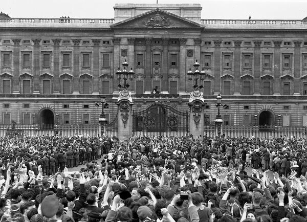 Огромная толпа, собравшаяся перед Букингемским дворцом в Лондоне в День Победы 8 мая 1945 года, приветствует королевскую семью на балконе через несколько минут после официального объявления о безоговорочной капитуляции Германии. Слева направо: принцесса Елизавета, Королева Елизавета, Король Георг VI и принцесса Маргарет. - Sputnik Беларусь