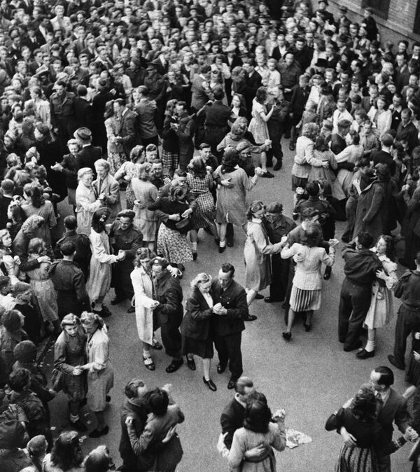 Голландский город Энсхеде, Нидерланды, во время празднования Дня Победы в мае 1945 года. Мужчины и женщины танцуют на площади. - Sputnik Беларусь