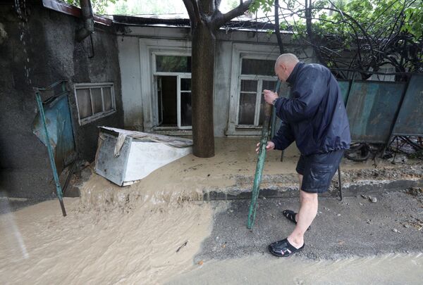 Мужчина у дома, пострадавшего от наводнения после сильного дождя в Ялте. - Sputnik Беларусь