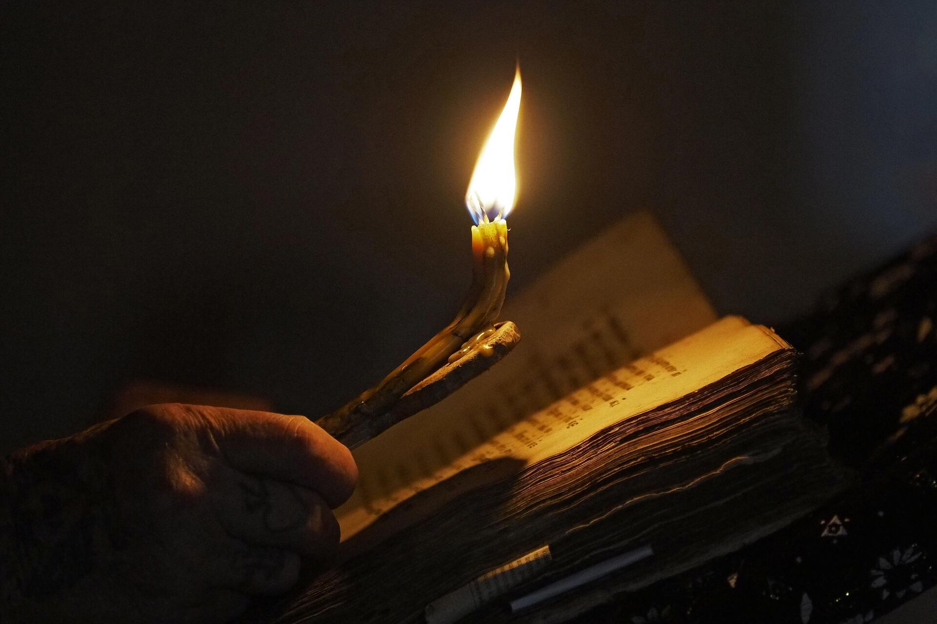 Верующий держит свечу во время молитвы в храме Успения Пресвятой Богородицы - Sputnik Беларусь, 1920, 05.05.2023