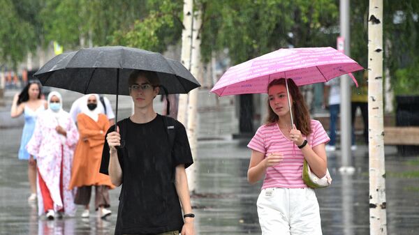 Молодые люди во время дождя на одной из улиц - Sputnik Беларусь