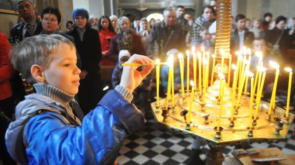 Мальчик зажигает свечу в храме - Sputnik Беларусь