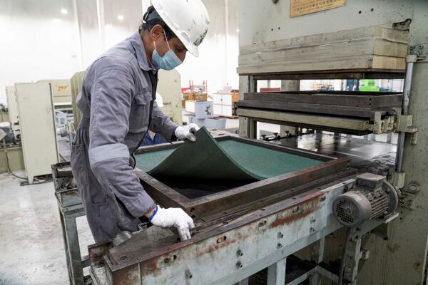 Сотрудники перерабатывающего завода сортируют и измельчают старые шины, чтобы затем изготовить коврики для пола. - Sputnik Беларусь