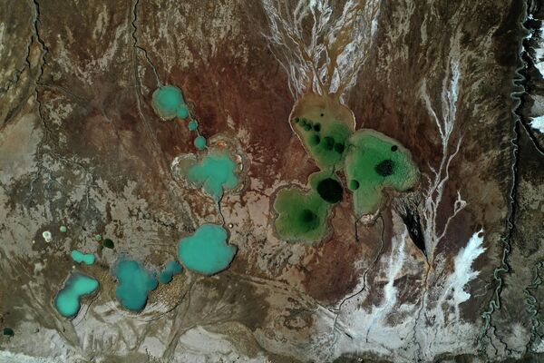 На поверхности высохших прудов-испарителей Мертвого моря недалеко от южного израильского курорта Неве-Зоар видны кристаллизованные минералы и воронки, заполненные водой. - Sputnik Беларусь