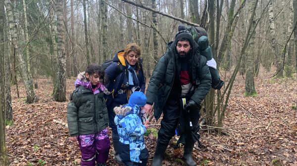 Мигранты перелазят через колючий забор на белорусско-польской границе - Sputnik Беларусь